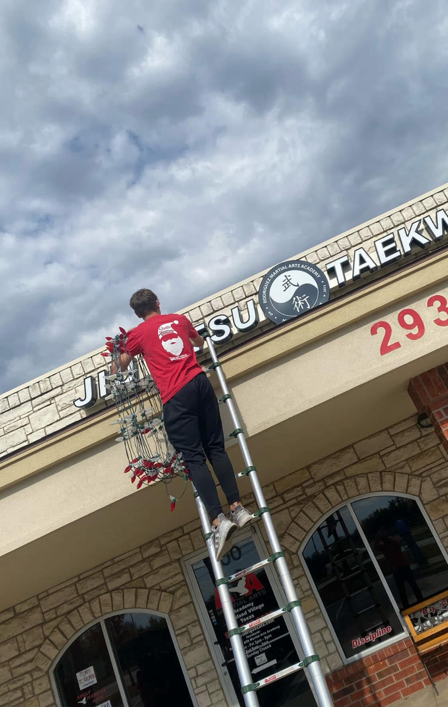NTX Christmas crew member installing lights on commercial building