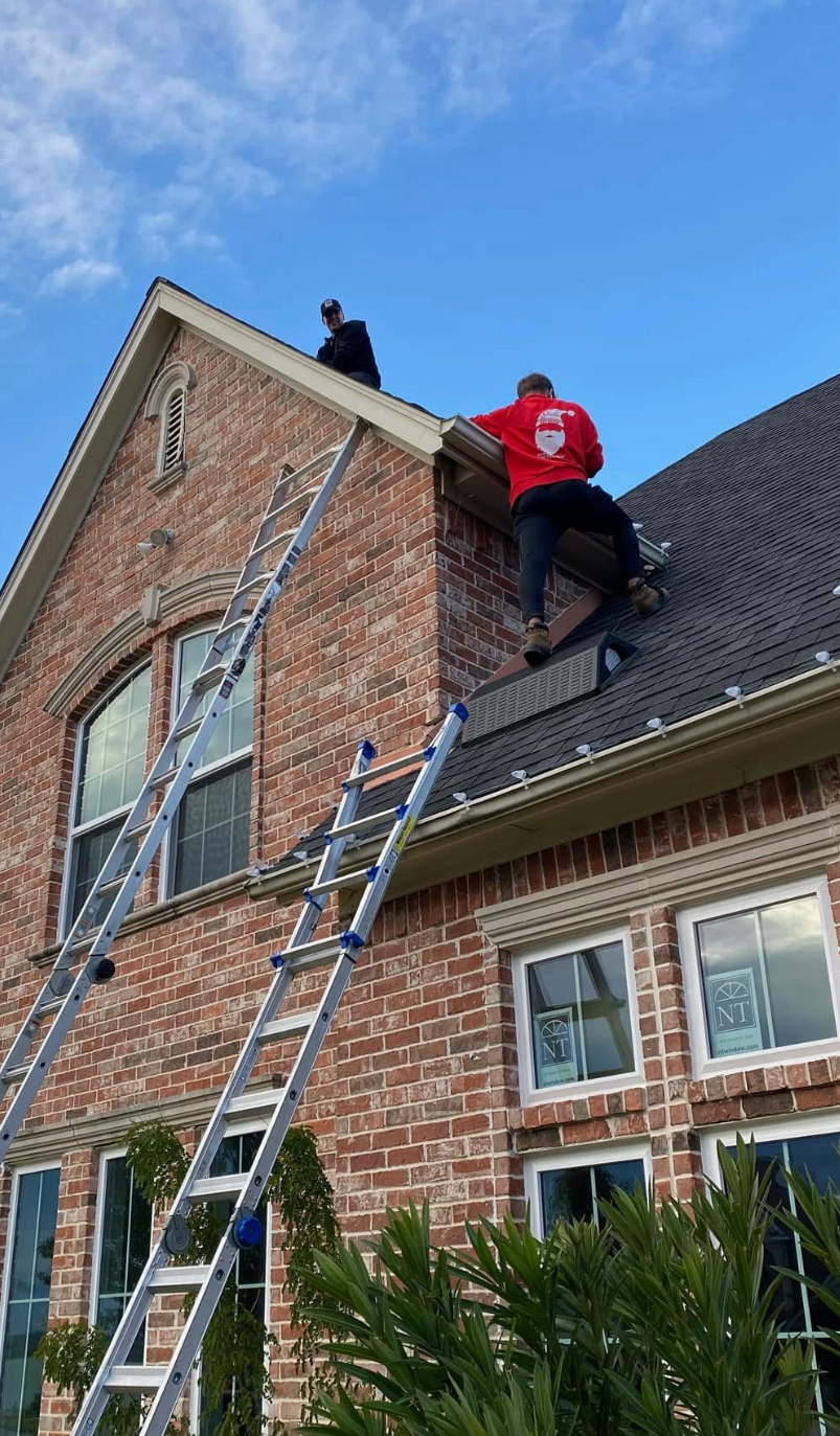 NTX Christmas crew member climbing residential roof with ladder
