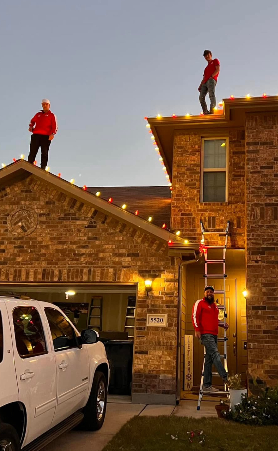 NTX Christmas team working together on residential rooftop at dusk